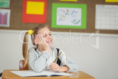 Smiling pupil daydreaming in a classroom