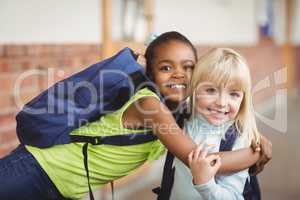 Cute pupils embracing at corridor