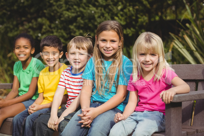 Smiling classmates sitting on bench