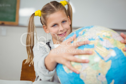 Cute pupil holding globe in a classroom