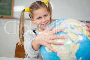 Cute pupil holding globe in a classroom