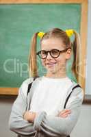 Cute pupil posing with arms crossed in a classroom