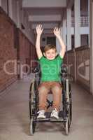 Smiling student in a wheelchair with arms raised