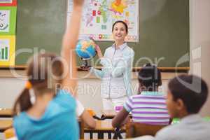 Pupils listening to their teacher holding globe