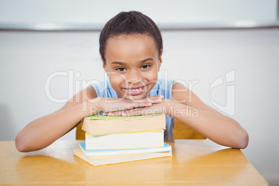 Smiling pupil resting head on a stack of books