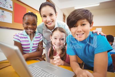 Teacher using laptop with pupils