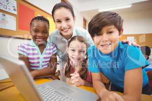 Teacher using laptop with pupils