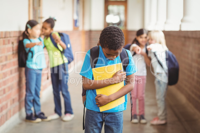 Sad pupil being bullied by classmates at corridor