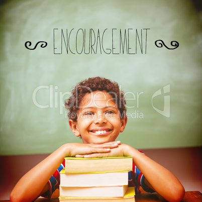 Encouragement against little boy with stack of books in classroo