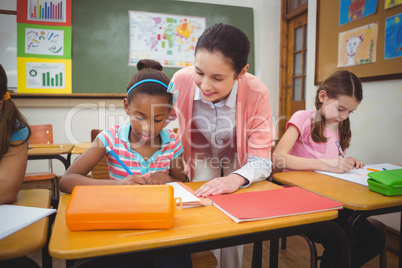 Pupil and teacher at desk in classroom