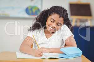 Cute pupil working at her desk in a classroom