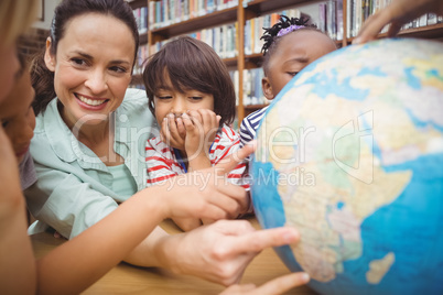 Pupils and teacher looking at globe in library