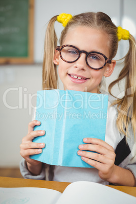 Cute pupil reading book in a classroom