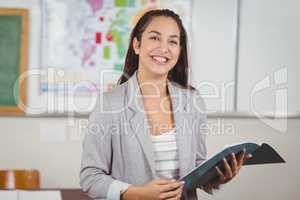 Pretty teacher holding notebook in a classroom