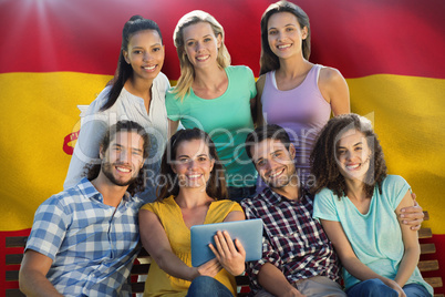 Composite image of smiling friends in the park using tablet pc