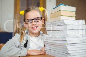 Smiling pupil next to stack of books on her desk