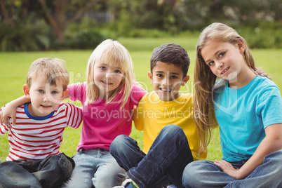 Smiling classmates sitting in grass