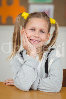 Cute pupil sitting at her desk in a classroom