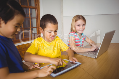 Cute pupils in class using laptop and tablet