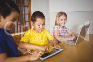 Cute pupils in class using laptop and tablet