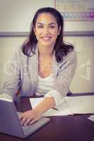 Pretty teacher working with laptop in a classroom