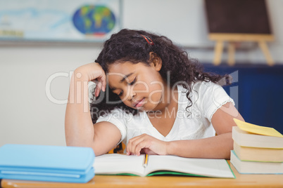 Concentrated pupil reading notepad in a classroom