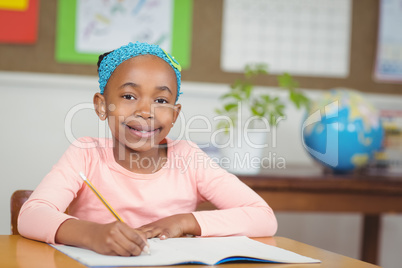 Cute pupil working at her desk in a classroom