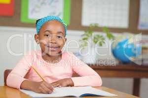 Cute pupil working at her desk in a classroom