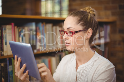 Blonde teacher using tablet in the library