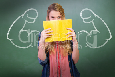 Composite image of student covering face with book in library