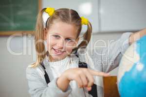 Cute pupil pointing on globe in a classroom