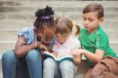 Students sitting on steps and reading a book