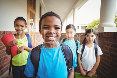 Cute pupils holding notebooks at corridor