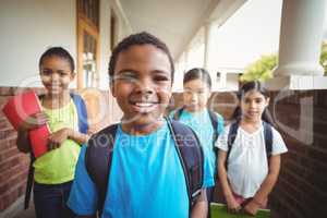 Cute pupils holding notebooks at corridor