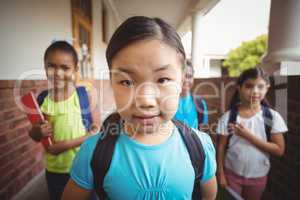 Cute pupils holding notebooks at corridor