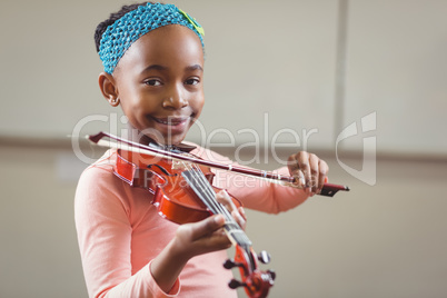 Smiling pupil playing violin in a classroom