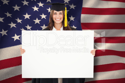 Composite image of a woman in her graduation gown holds a blank