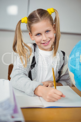 Cute pupil working at her desk in a classroom