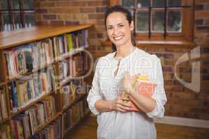 Smiling teacher holding books in her hands