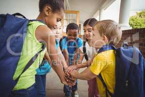 Happy pupils putting hands together at corridor