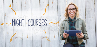 Night courses against smiling blonde in glasses using tablet pc
