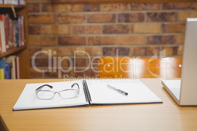 Desk with laptop, glasses and ledger on it
