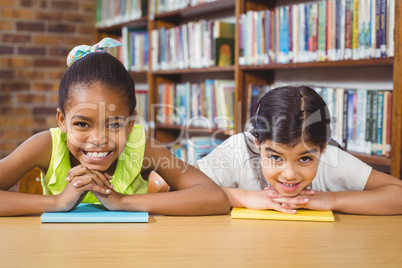 Smiling pupils leaning on books in the library