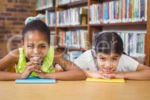 Smiling pupils leaning on books in the library