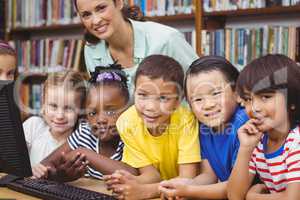 Pupils and teacher in the library using computer