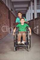 Smiling student in a wheelchair and friend pushing