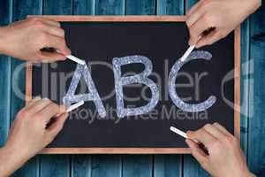 Composite image of multiple hands writing with chalk