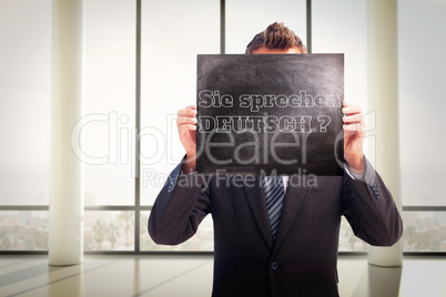 Composite image of businessman showing board