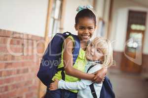 Cute pupils embracing at corridor