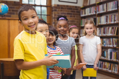 Pupils holding books from shelf in library